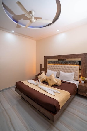 A modern hotel room with a large bed, a ceiling fan, and a nightstand with a lamp. - Hotel Royce Executive, Near US Consulate (Mumbai)