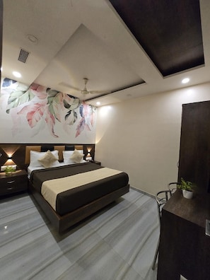 A modern bedroom with a large bed, a ceiling fan, and a wall-mounted TV. - Hotel Royce Executive, Near US Consulate (Mumbai)