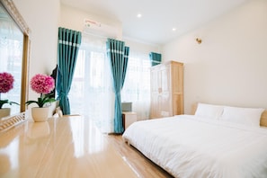 A hotel room with a bed, a desk with a chair, a wardrobe, and a window with curtains. - La Teisu Airport Hotel (Hanoi)