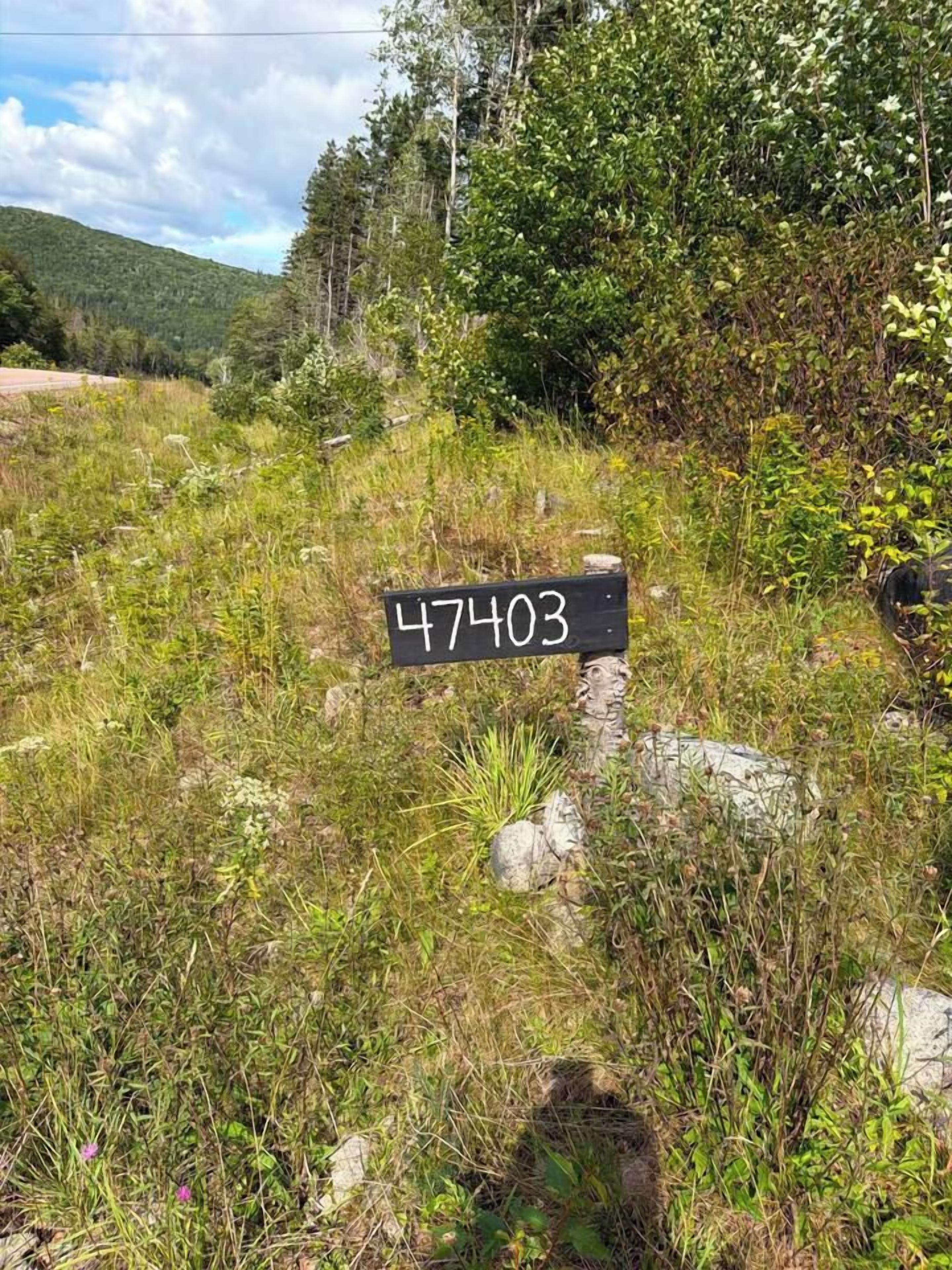 A sign with the number 47403 in a natural setting with grass and trees.