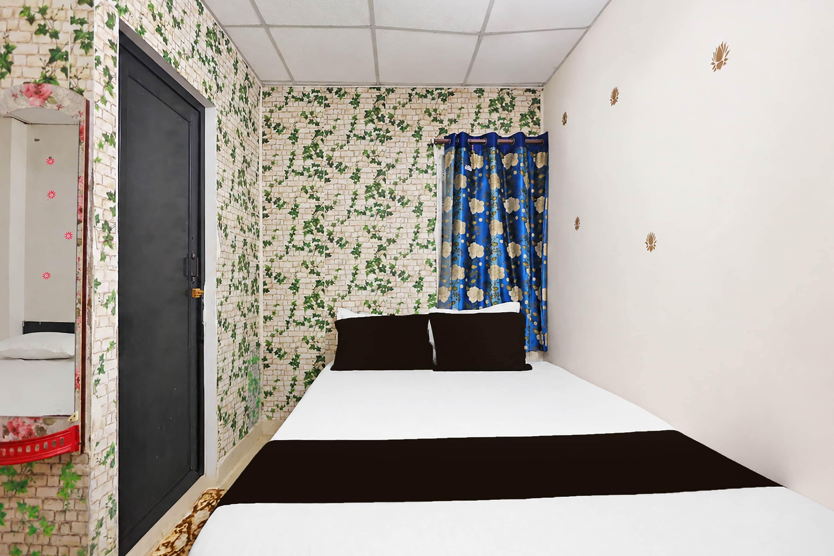 A narrow room with a bed, a door, and a wall with a brick pattern.