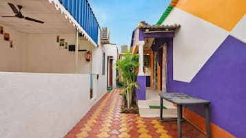A narrow alleyway with colorful buildings, a tiled walkway, and a small table.
