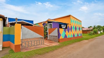 Un hotel con fachada colorida, un letrero que indica que es administrado por OYO y un área de entrada pavimentada.