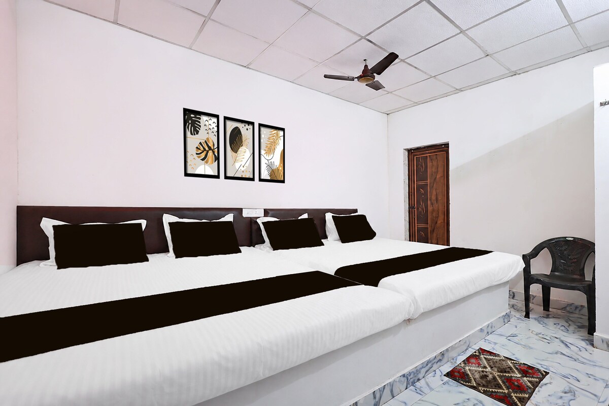 Habitación de hotel con una cama grande, un ventilador de techo y tres cuadros enmarcados en la pared.