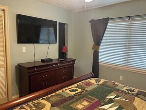 A bedroom with a bed, a dresser, a television mounted on the wall, and a window with blinds. - Creek & Mountain Views, Free Tickets to Area Attractions (Gatlinburg)
