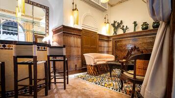 Um interior tradicional com sofá, cadeiras, tapete estampado e arte decorativa na parede.