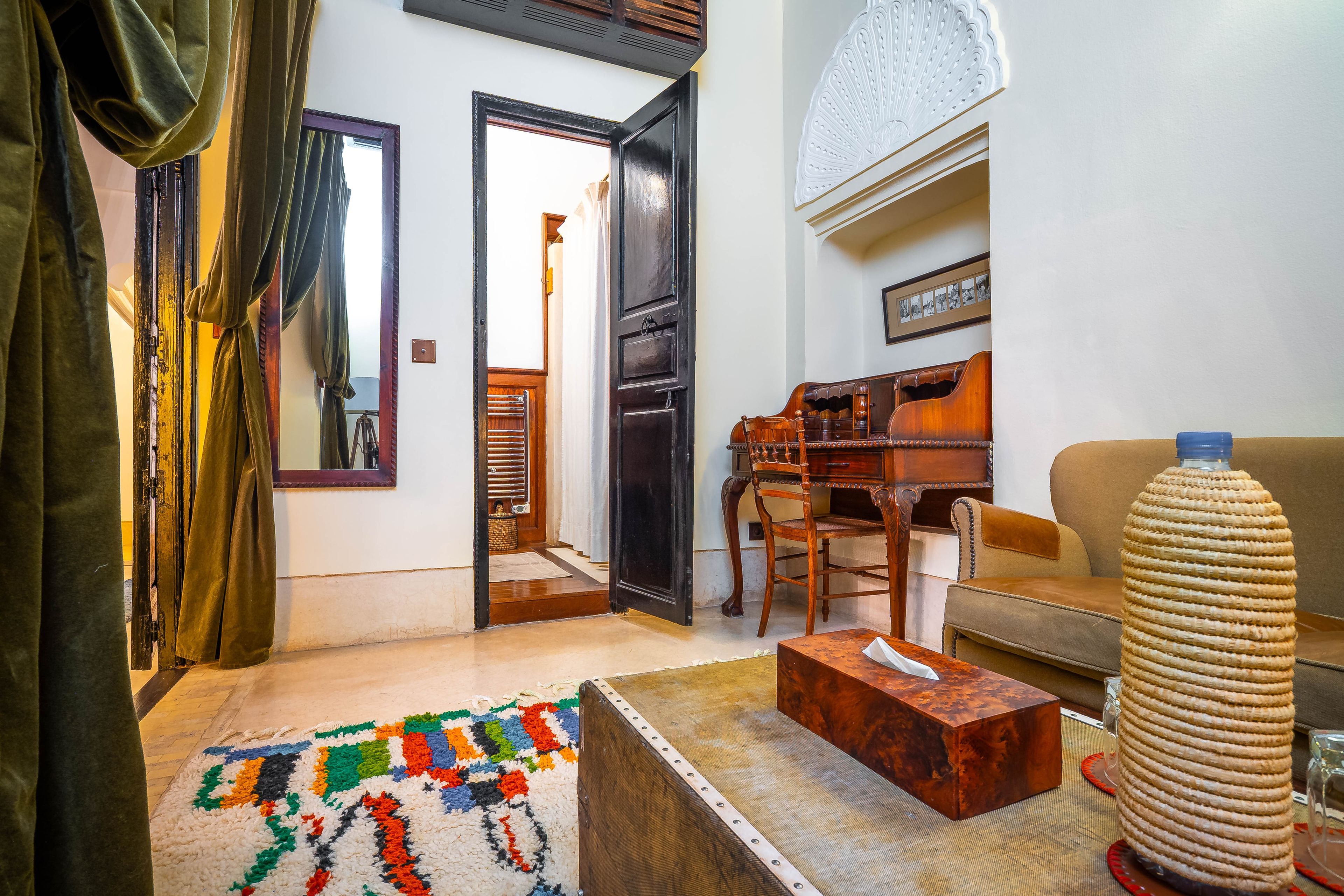 Una sala de estar con un sofá, una mesa de centro, un tapete estampado, un aparador de madera y un objeto decorativo.