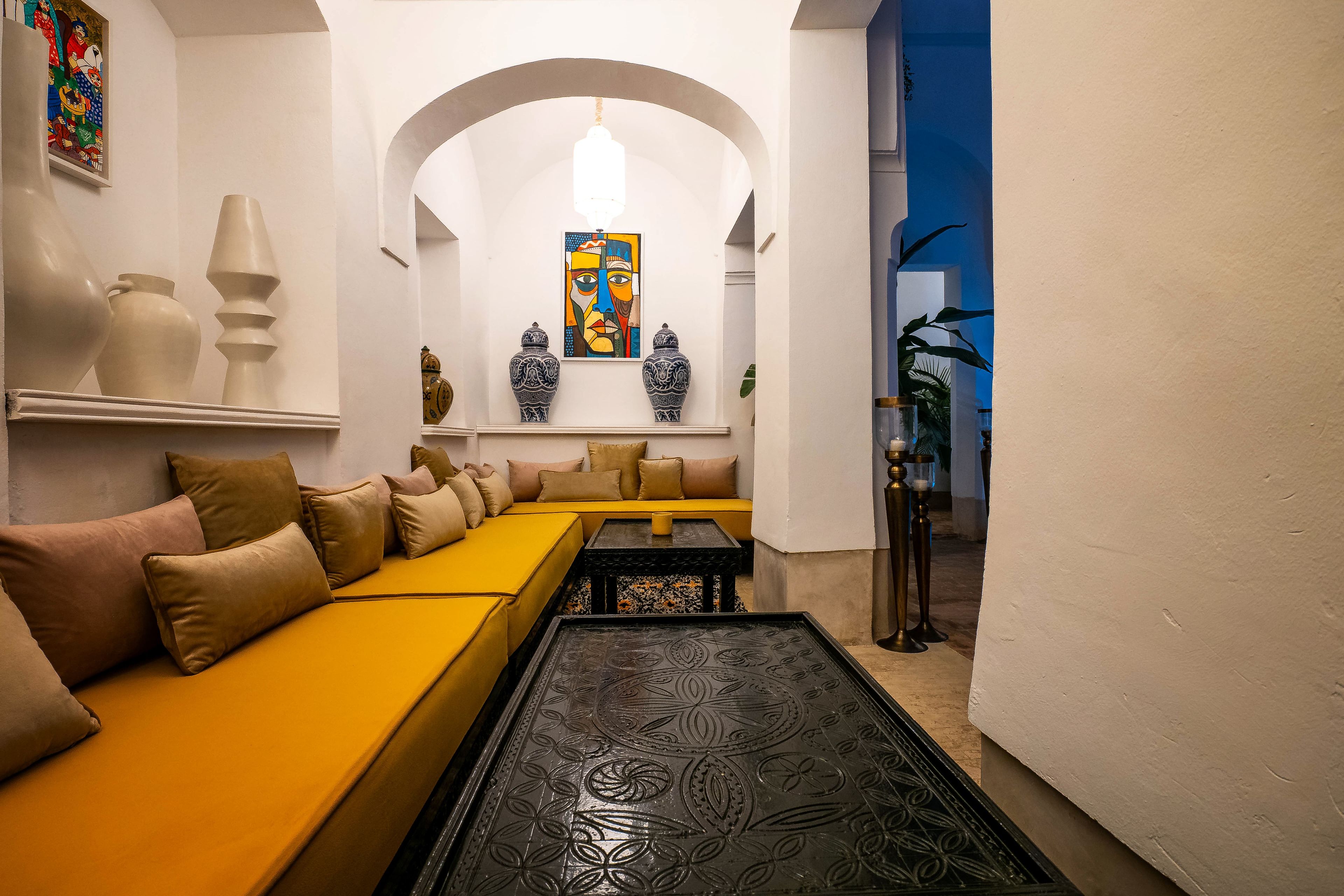 Un interior moderno con un sofá amarillo, jarrones decorativos y una mesa de centro estampada.