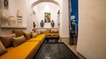 Un interior moderno con un sofá amarillo, jarrones decorativos y una mesa de centro estampada.