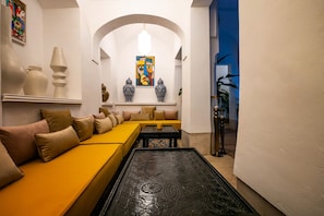 Um interior moderno com um sofá amarelo, vasos decorativos e uma mesa de centro estampada.