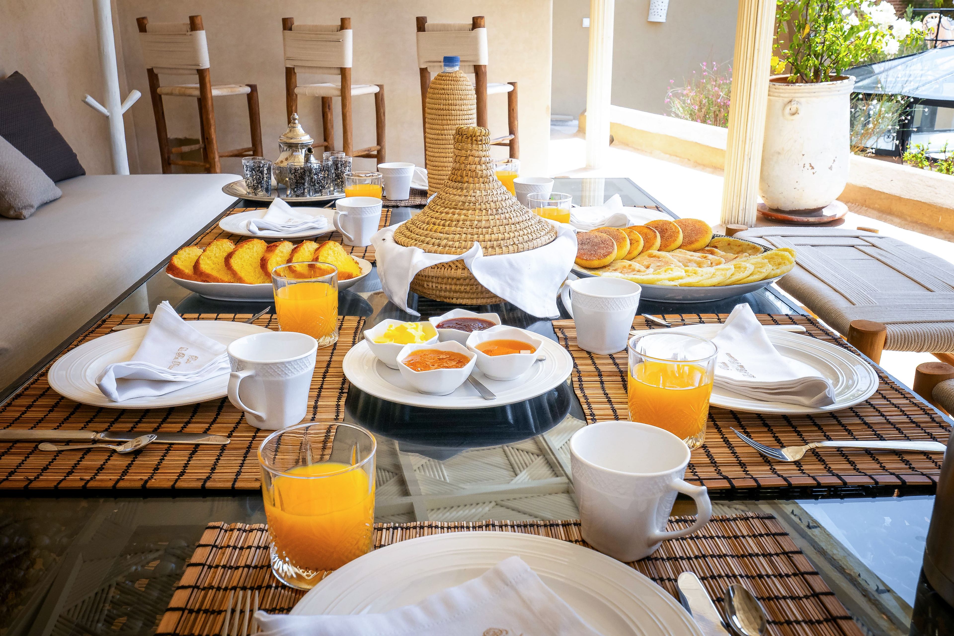 Buffet de café da manhã com diversos pratos, bebidas e uma peça decorativa sobre a mesa.