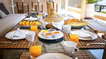 Buffet de café da manhã com diversos pratos, bebidas e uma peça decorativa sobre a mesa.