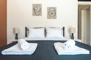 Habitación de hotel con una cama, dos lámparas de pared y dos obras de arte abstracto.