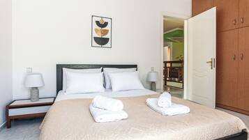 A hotel room with a bed, two bedside tables, a nightstand, a wooden wardrobe, and a framed artwork on the wall.