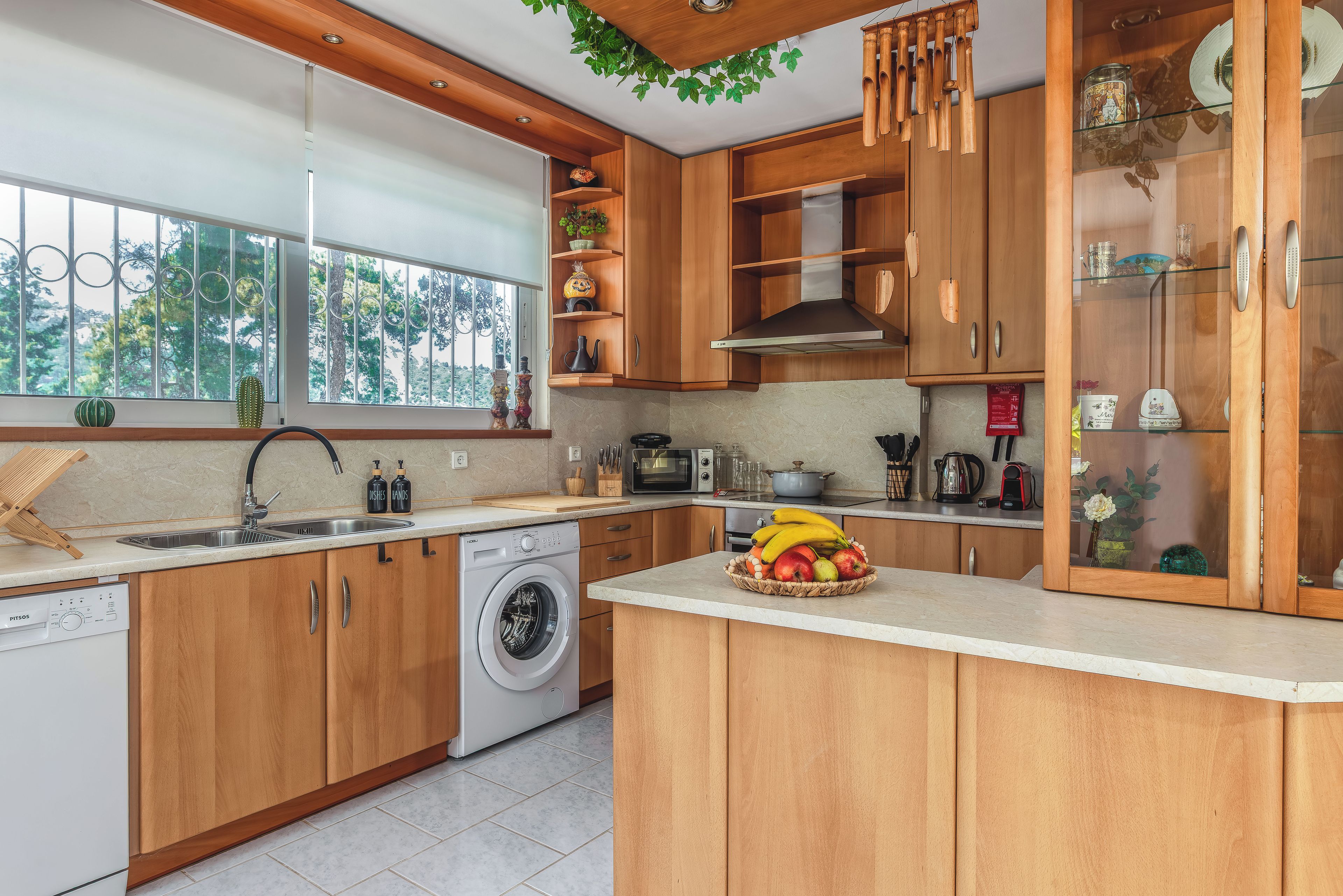 Een moderne keuken met houten kastjes, een ingebouwde wasmachine en een fruitschaal op het aanrecht.