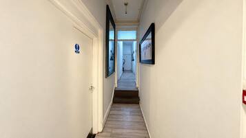 A narrow hallway with a door on the left and a framed picture on the right.