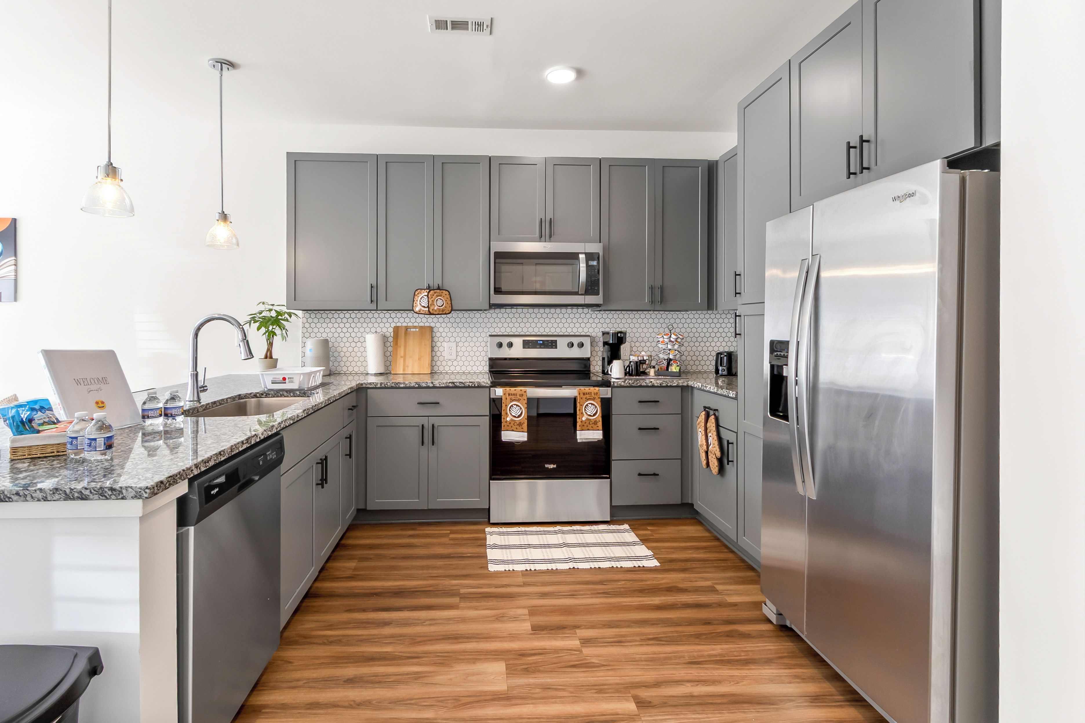 A modern kitchen with grey cabinets, stainless steel appliances, a microwave, oven, and refrigerator.