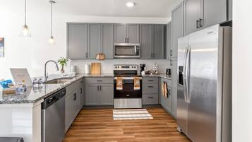 A modern kitchen with grey cabinets, stainless steel appliances, a microwave, oven, and refrigerator.
