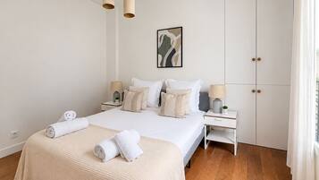 A hotel room with a large bed, two bedside tables, a wardrobe, and a window with curtains.