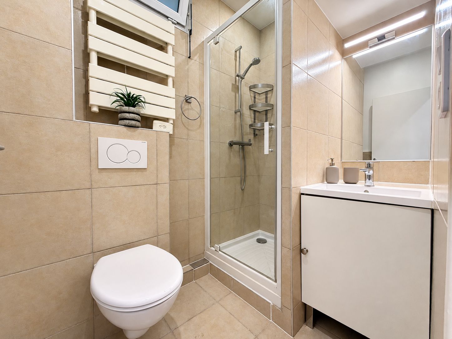A modern bathroom with a toilet, a glass-enclosed shower, and a sink with a mirror.