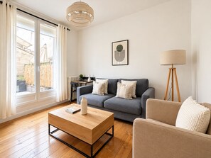 A modern living room with a grey sofa, a wooden coffee table, a floor lamp, and a radiator. - Magnifique Appartement Levallois Perret (Levallois-Perret)