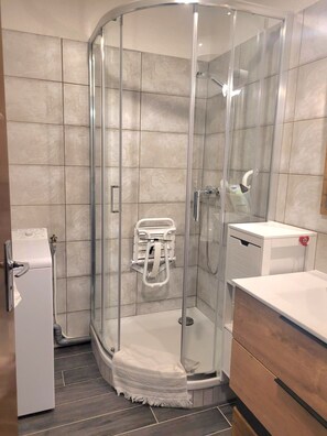 Ein modernes Badezimmer mit einer gläsernen Dusche, einem weißen Handtuchhalter und einem Holzbadschrank.