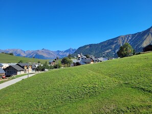 Ein ländliches Dorf mit Häusern an einem Hang, einer Kirche und Bergen im Hintergrund.