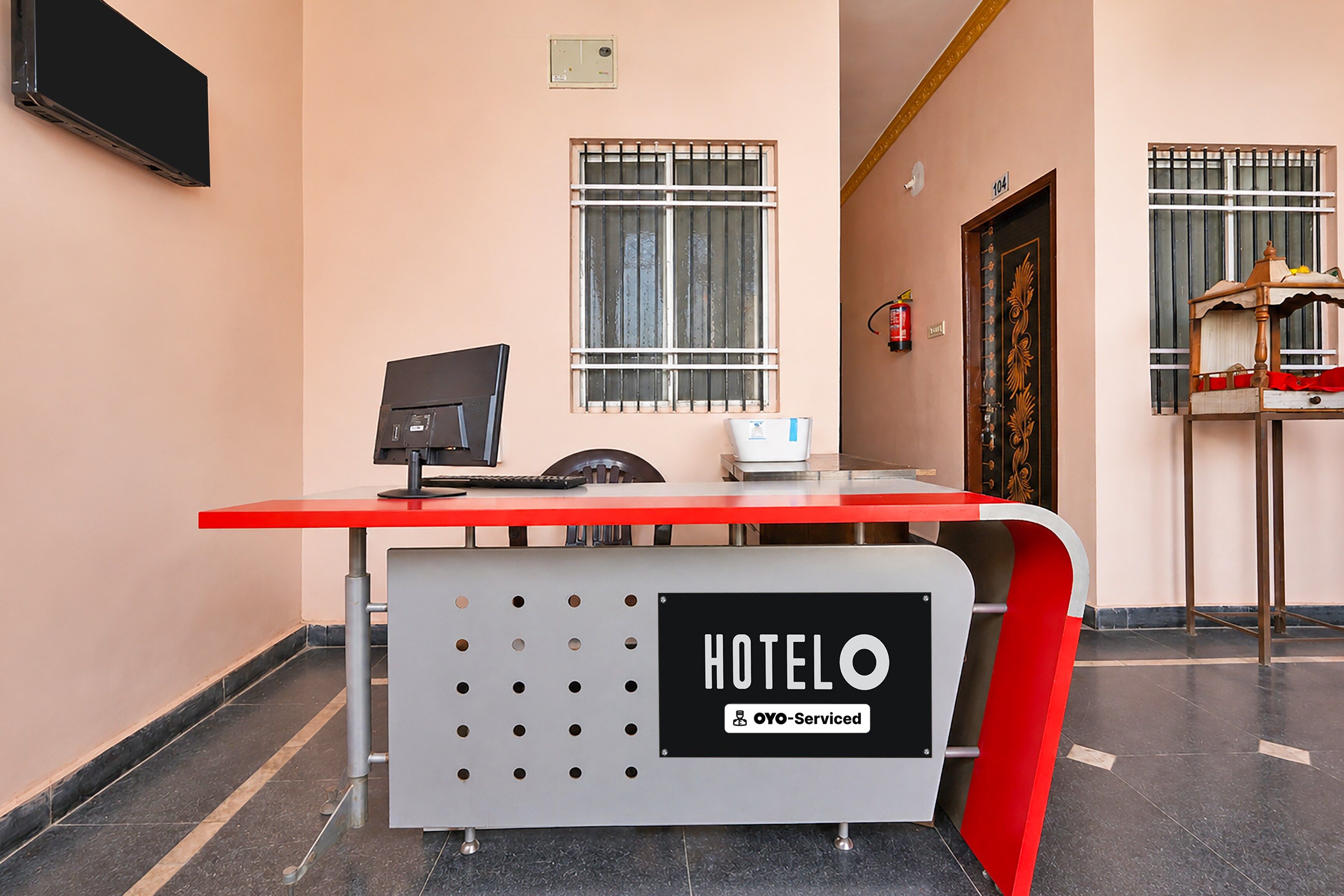 A hotel reception desk with a computer, a scale, and a fire extinguisher.