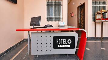 A hotel reception desk with a computer, a scale, and a fire extinguisher.