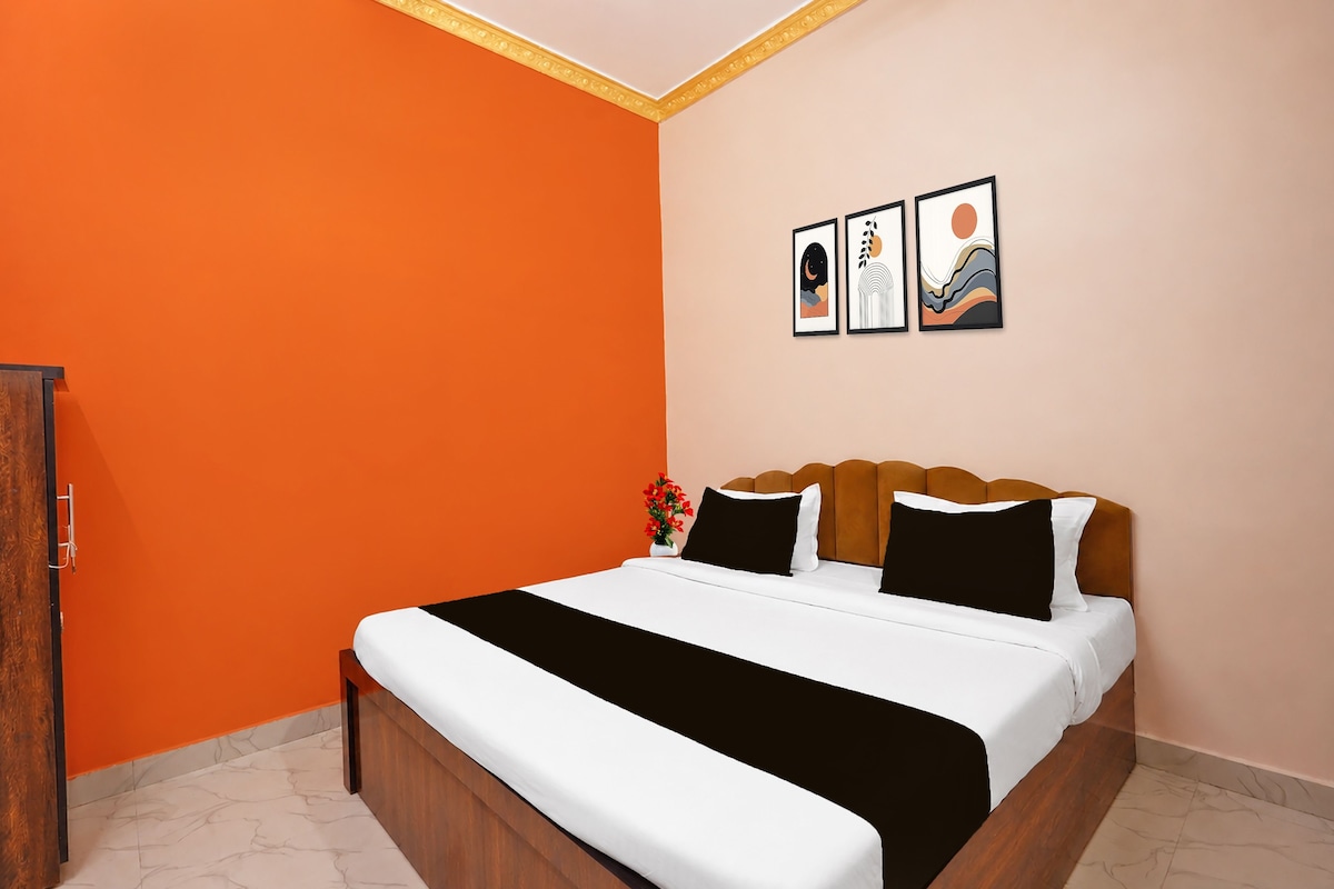Un dormitorio con una cama, una mesita de noche y una pared con tres cuadros enmarcados.