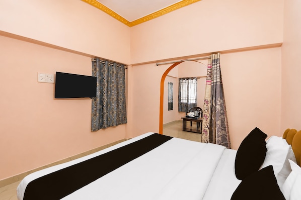 A hotel room with a bed, a television mounted on the wall, and a bathroom visible through an archway.