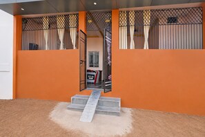 A hotel entrance with a metal gate, a staircase leading to the entrance, and a sign indicating the hotel name.