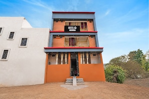 A multi-story hotel with a modern design, featuring a prominent signboard and a staircase leading to the entrance.