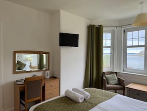 A hotel room with a bed, a desk, a chair, a television, and a window with curtains. - Lochranza Country Inn (Isle of Arran)