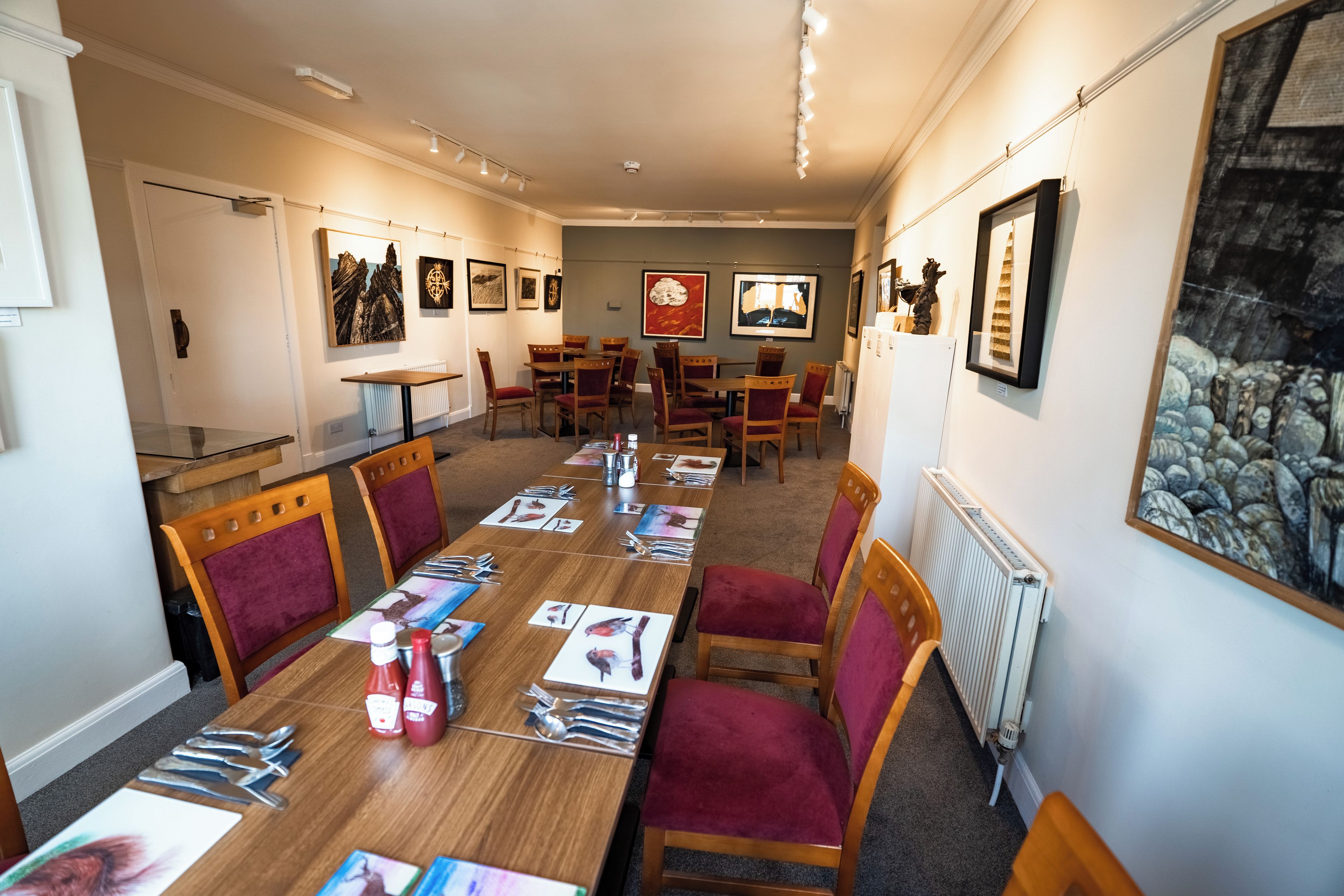 A conference room with a long table, chairs, and framed artwork on the walls.
