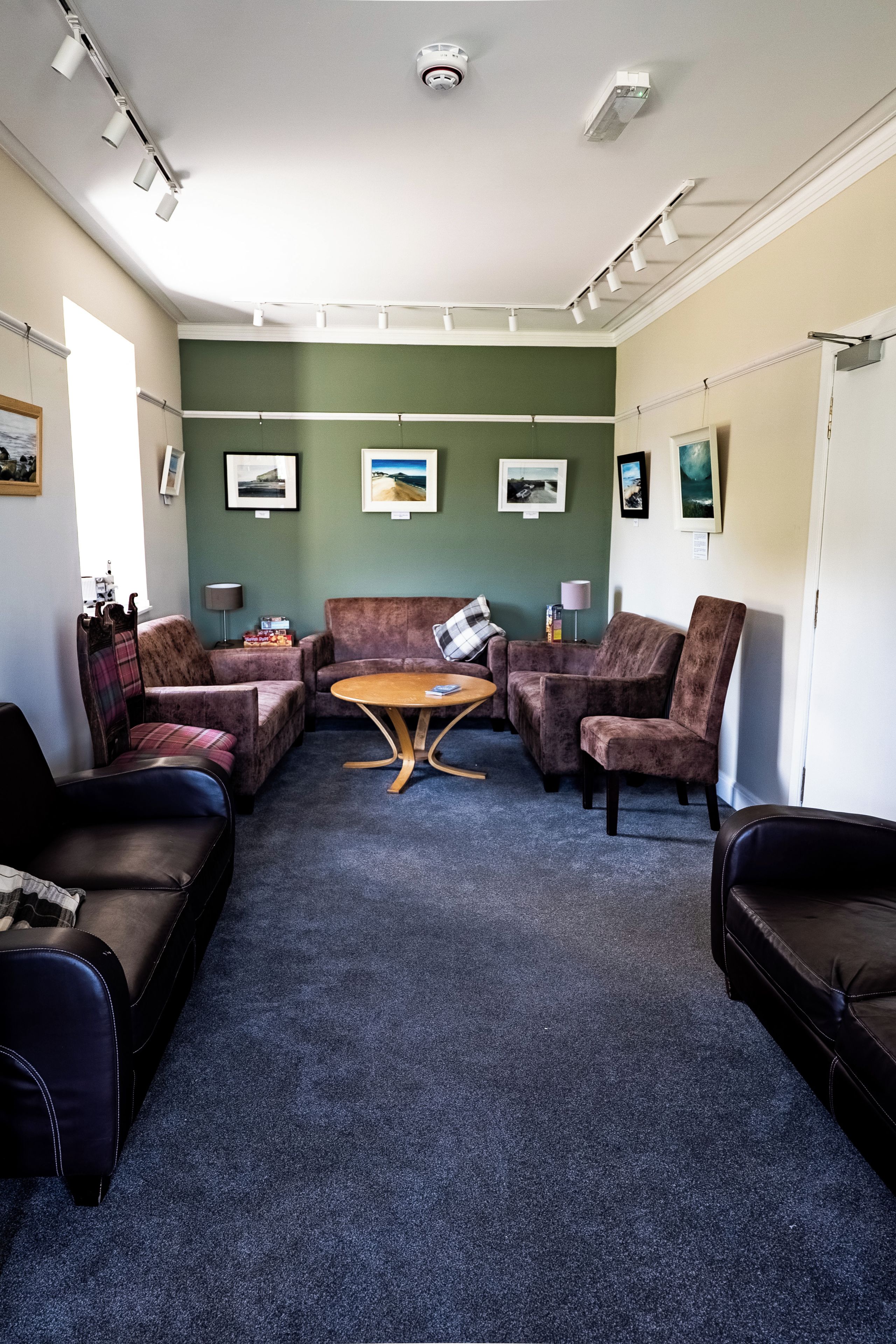 A room with a seating area featuring a brown sofa, a brown armchair, and a wooden coffee table.