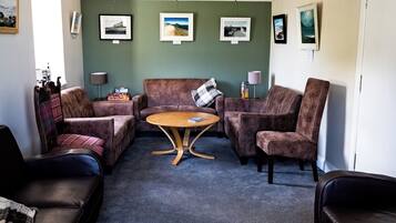 A room with a seating area featuring a brown sofa, a brown armchair, and a wooden coffee table.