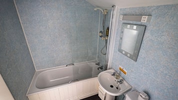 A bathroom with a bathtub, a sink, and a mirror.