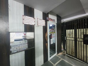 A building entrance with a metal gate, a door with a glass panel, and several signs on the wall. - Oly Hotel Star Inn (New Delhi)