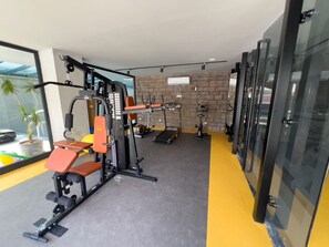 A gym with exercise equipment, a brick wall, and a window with a plant. - Qoople Prive 42 - Cozy 1-bedroom apartment in Alanya (Alanya)