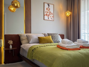 A hotel room with a bed, pillows, a green blanket, and towels. - Qoople Prive 42 - Cozy 1-bedroom apartment in Alanya (Alanya)