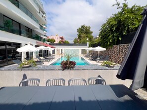 A pool area with lounge chairs, a table, and umbrellas. - Qoople Prive 42 - Cozy 1-bedroom apartment in Alanya (Alanya)