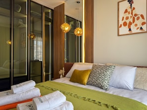 Ein modernes Hotelzimmer mit einem großen Bett, einer grünen Zudecke und einem Gemälde an der Wand.