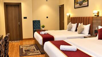 Une chambre d’hôtel avec deux lits, un ventilateur de plafond, un appareil de climatisation, un tableau au mur et un tapis à motifs.