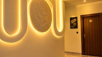 A hallway with a modern design, featuring a large illuminated number '10' on the wall and a circular art piece.