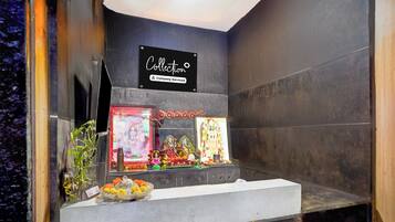 A shrine with religious icons, a sign indicating a collection, and a small altar with offerings.
