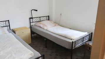 A single bed with a headboard, a bedside table, and a wall socket.