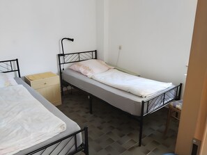A single bed with a headboard, a bedside table, and a wall socket.