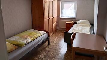 Ein Schlafzimmer mit einem Bett, einem Holzschrank, einem Schreibtisch und einem Fenster.