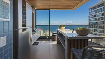 Een moderne keuken met een roestvrijstalen koelkast, een groot raam met uitzicht op zee, en een balkon met stadszicht.